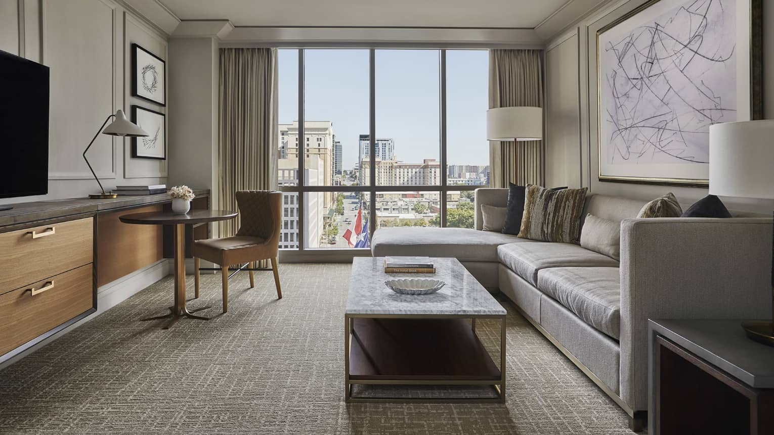 City View Suite, L-shaped sofa, marble coffee table with books, dresser, dining table, large window