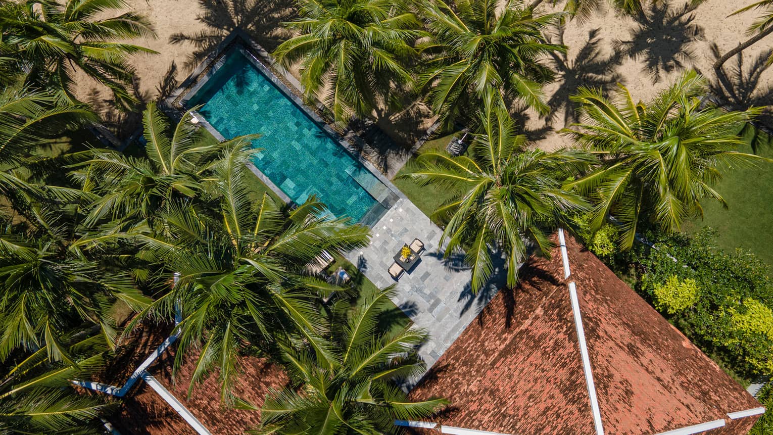 Aerial view of a tropical villa with a tiled roof, surrounded by lush palm trees, featuring a pool and a sunlit patio near a sandy beach.,Aerial view of a tropical villa with a tiled roof, surrounded by lush palm trees, featuring a pool and a sunlit patio near a sandy beach.,Aerial view of a tropical villa with a tiled roof, surrounded by lush palm trees, featuring a pool and a sunlit patio near a sandy beach.,Aerial view of a tropical villa with a tiled roof, surrounded by lush palm trees, featuring a pool and a sunlit patio near a sandy beach.