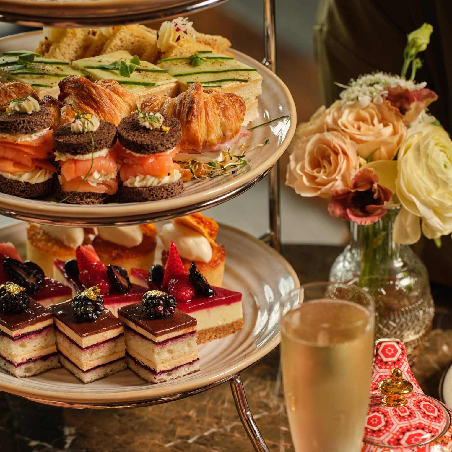 A three-tiered display of sweets beside a vase of flowers