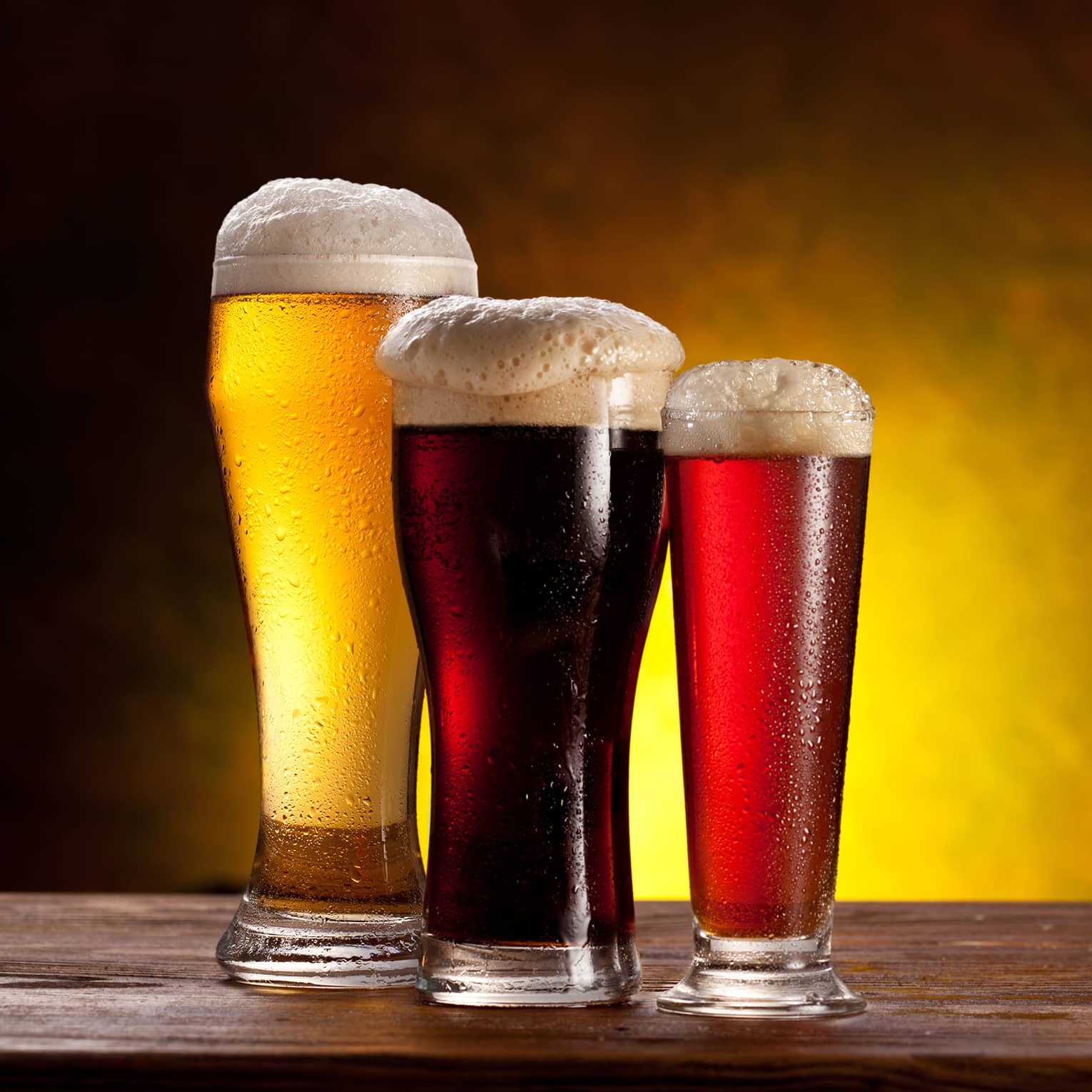 Three glasses of beer of varying colours.