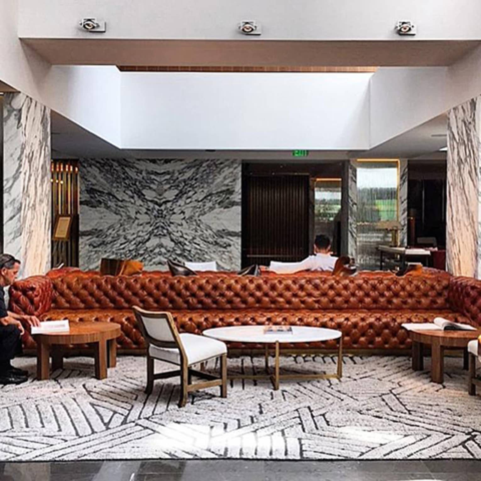 Lounge with long brown leather sofa, cocktail tables and chairs, rug