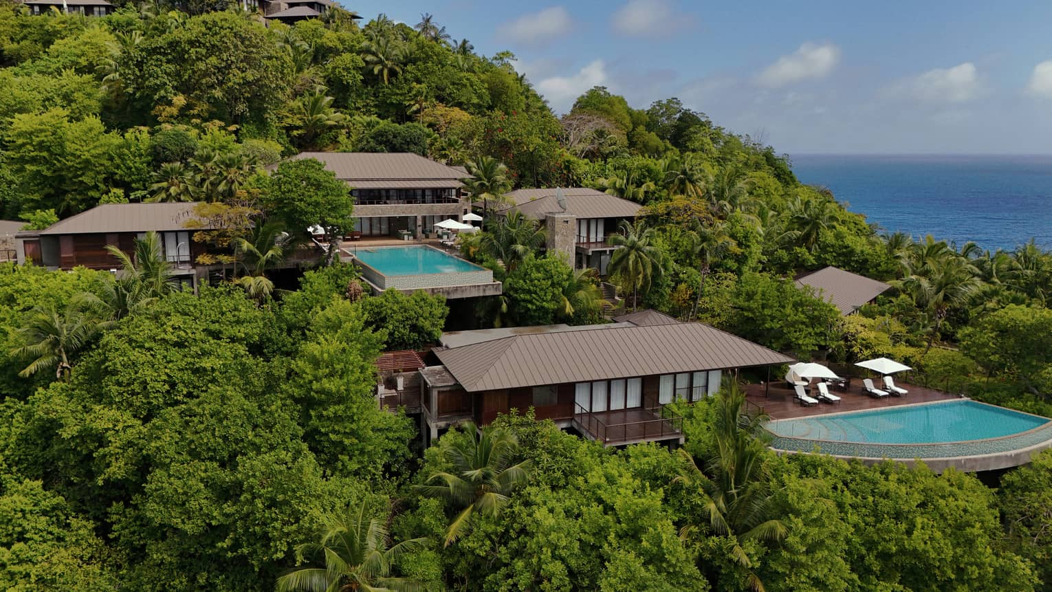 Aerial view of a large private residence with pool nestled on lush ocean-view hillside