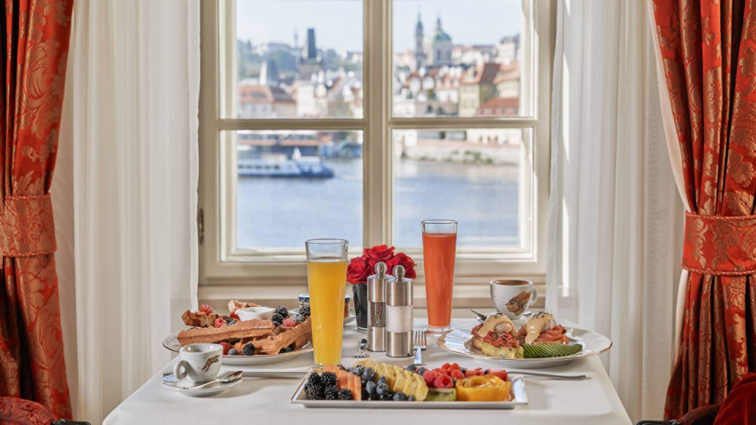 Table set for two with breakfast, window looks out to river and Prague Castle