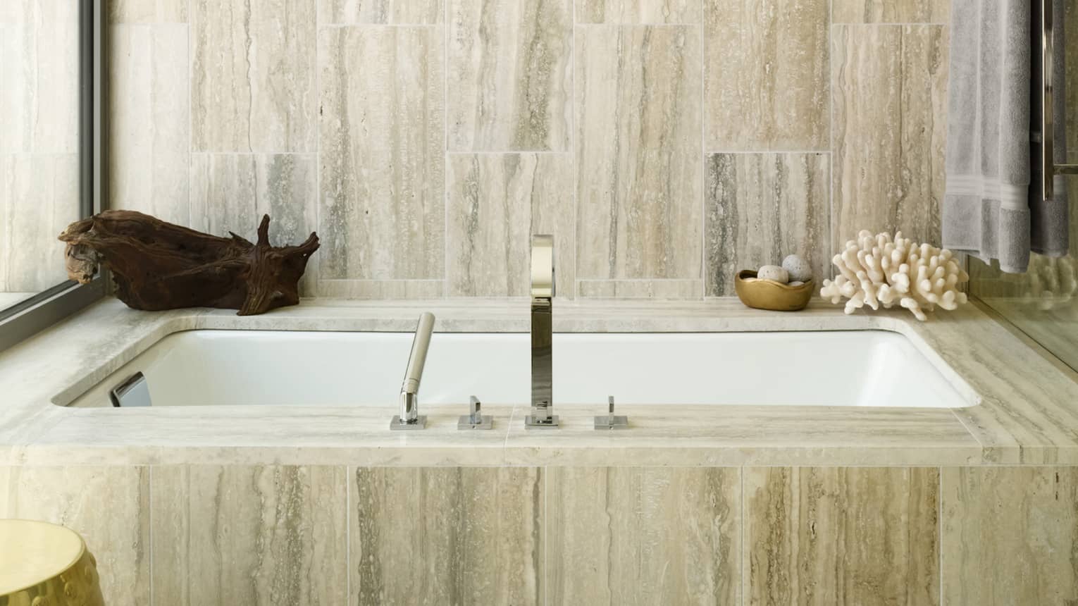 Luxury resort bathtub with a marble surround, chrome fixtures and decorative accents including driftwood and coral