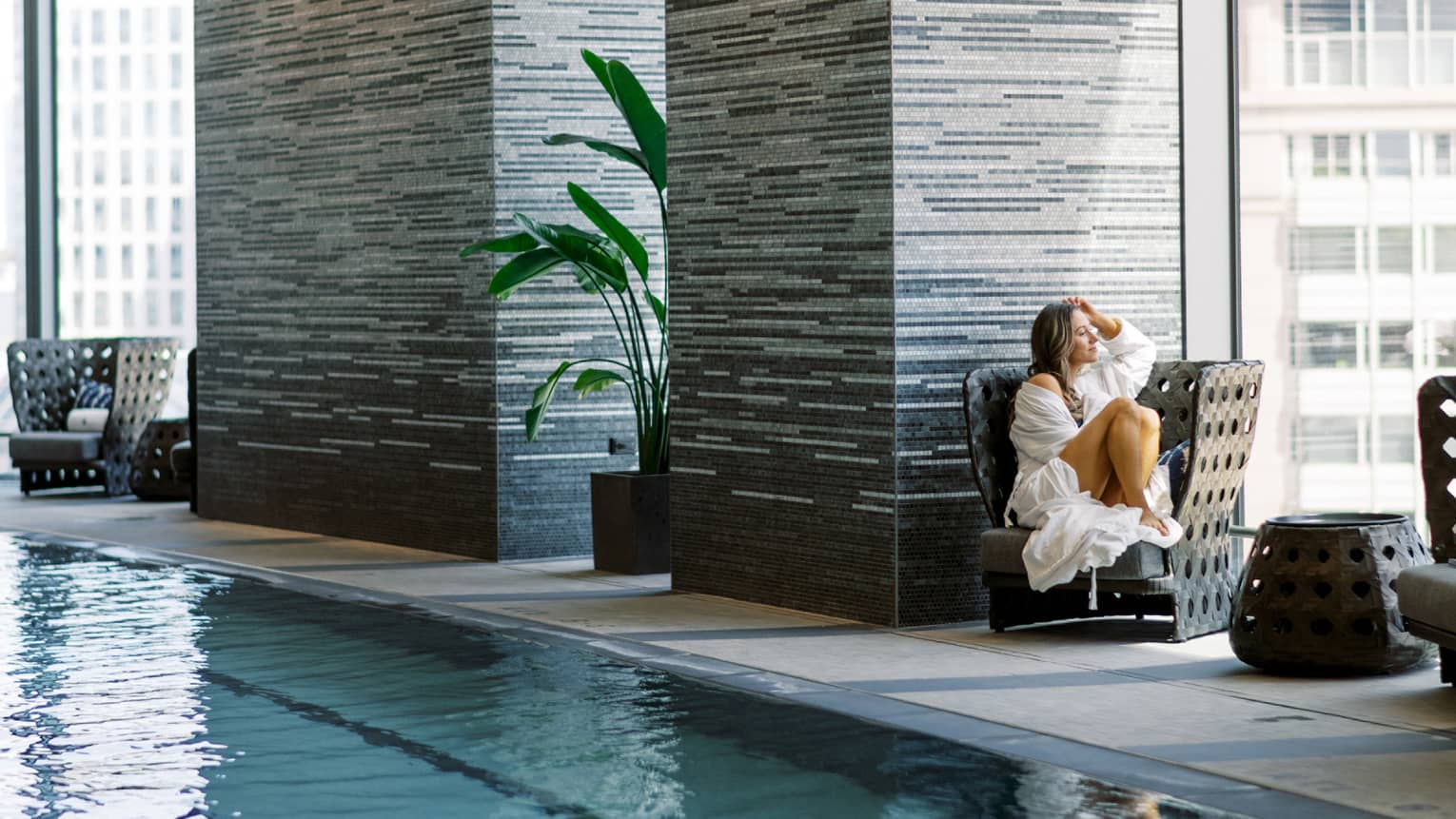 Guest sitting in a chair looking out the window beside the pool.
