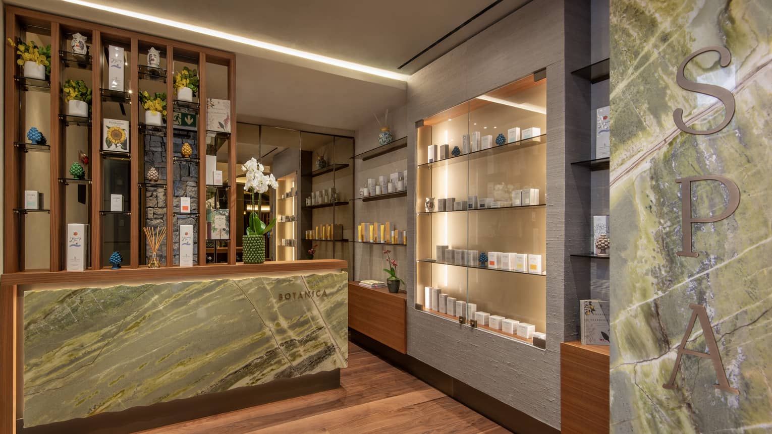 Spa reception area with marble desk and uplit wall with retail spa products
