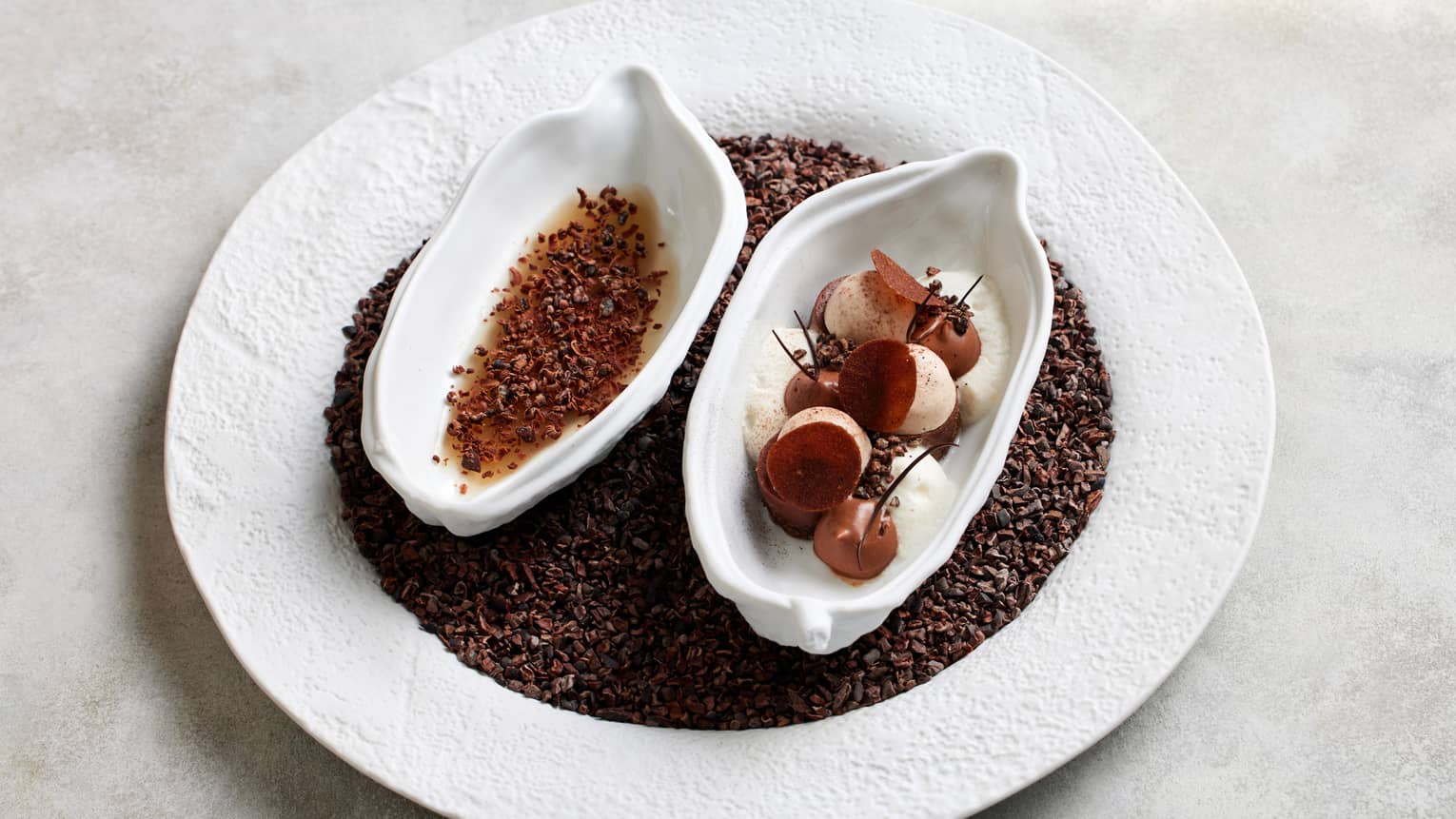 Selection of chocolates plated on ground cocoa beans on a white plate