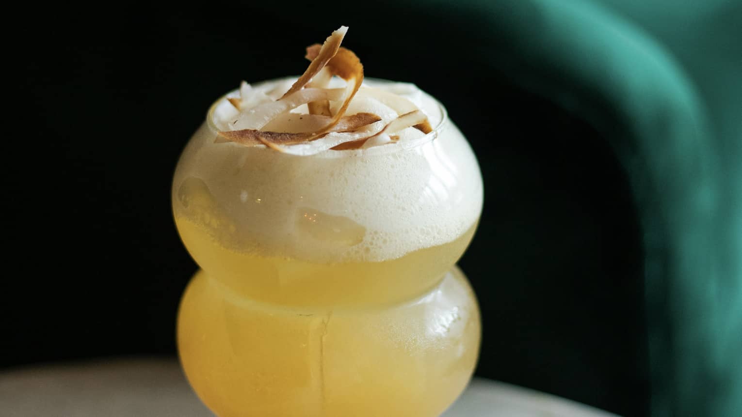 A small cocktail with toasted coconut garnish.