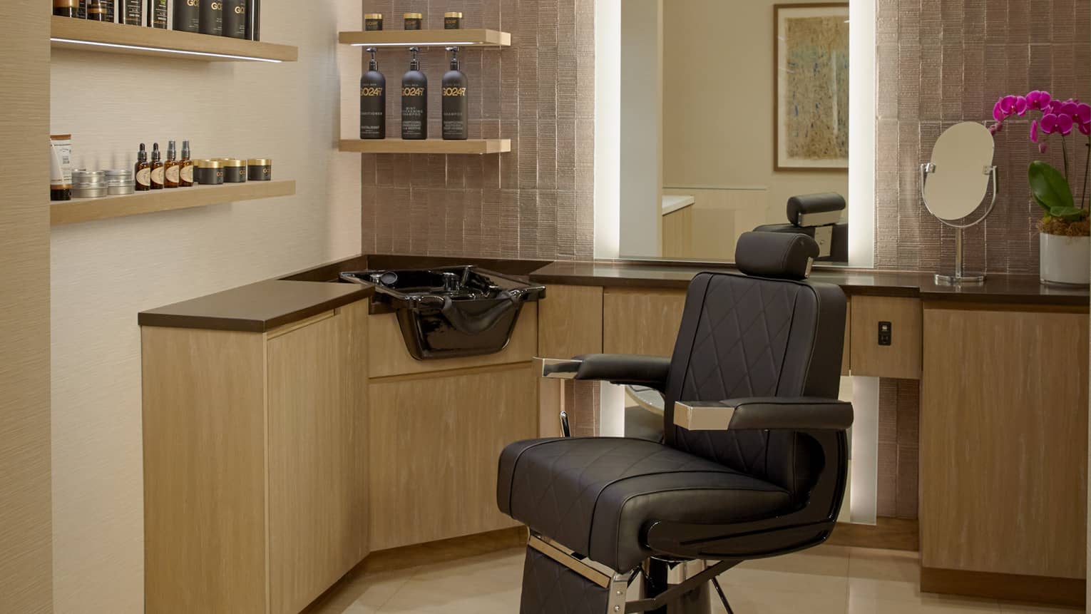 A salon chair next to a sink and shelves of hair products