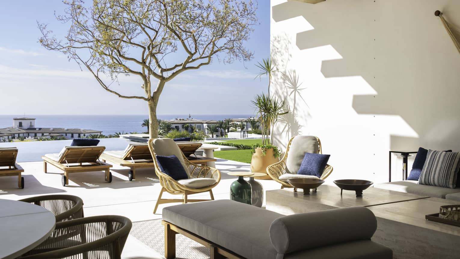 Covered outdoor terrace with lounge seating, opening up to pool terrace with ocean view