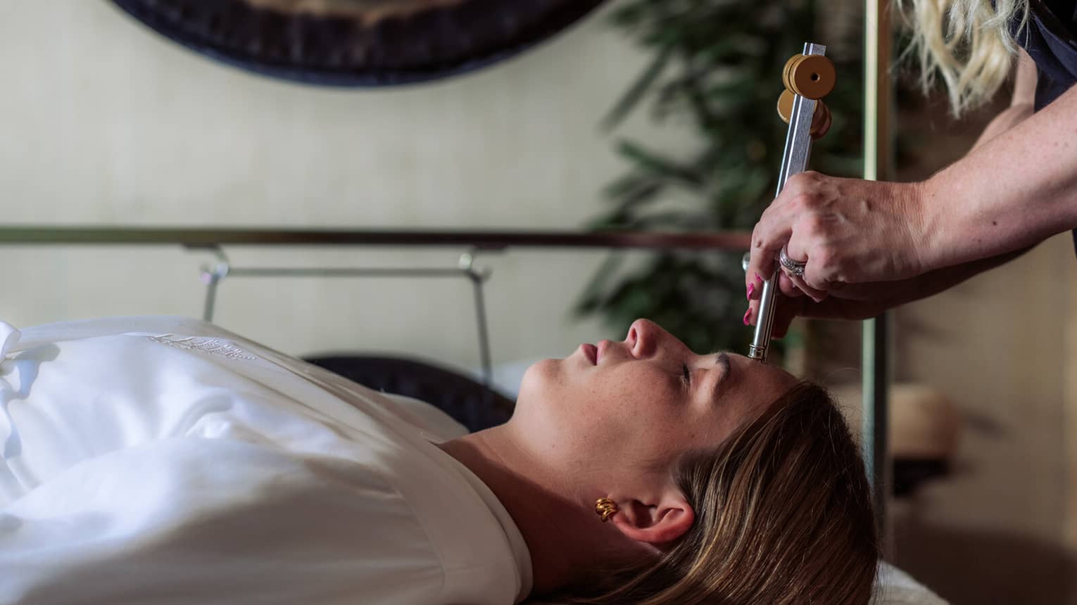 A woman receiving sound healing treatments at a spa.