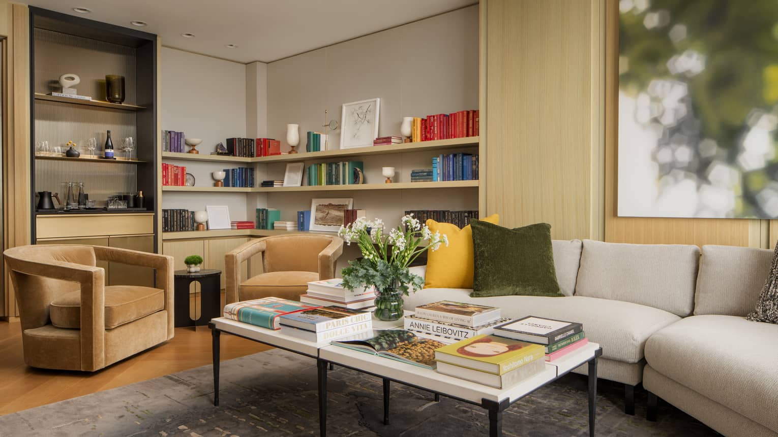 Office and living area of guest room with cream sofa, tan armchairs and built-in bookshelves