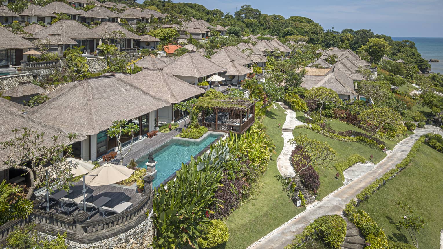 Aerial view of Royal Villa with pool, rolling green hills, ocean views