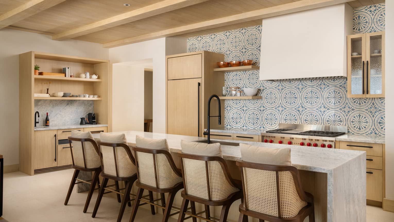 Luxury villa kitchen with mosaic tiled wall and marble island with five bar seats at Four Seasons Resort Cabo San Lucas at Cabo Del Sol