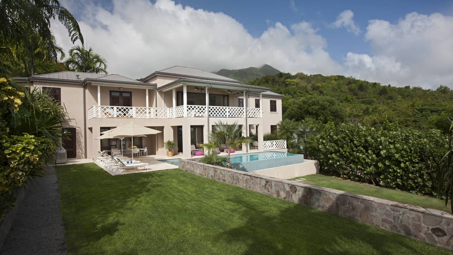 Two storey white villa and plunge pool surrounded by lush greenery