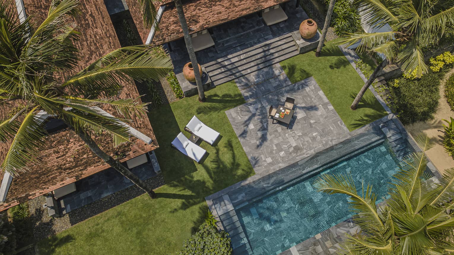 Aerial view of a private villa at luxury tropical resort, with private pool, stone terrace and dining table