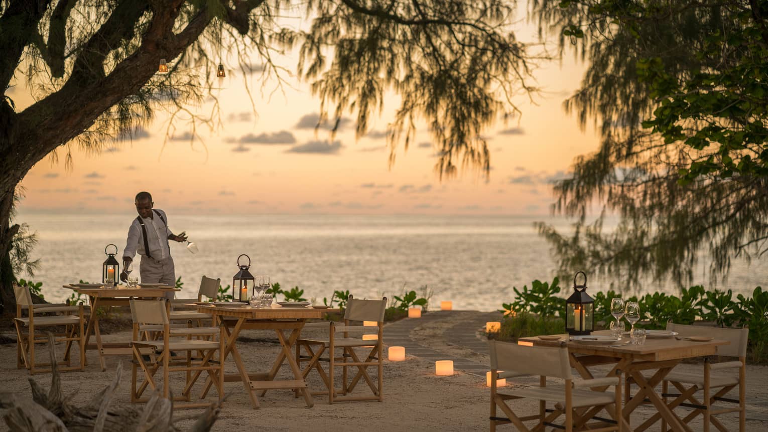 Lighthouse Restaurant on beach decorated with luminaries at sunset