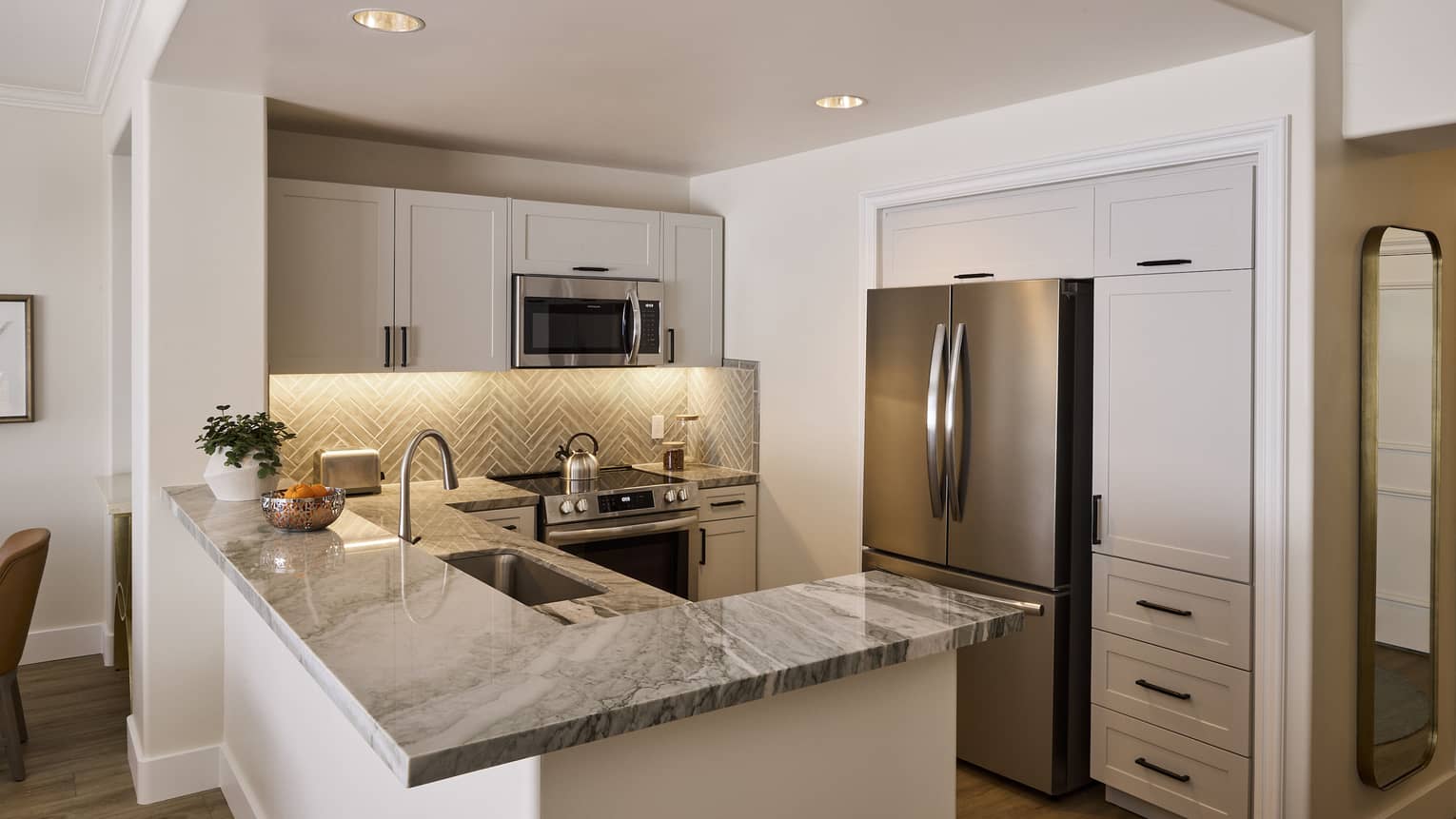 Sleek kitchen in private villa, featuring stainless steel appliances and chevron backsplash