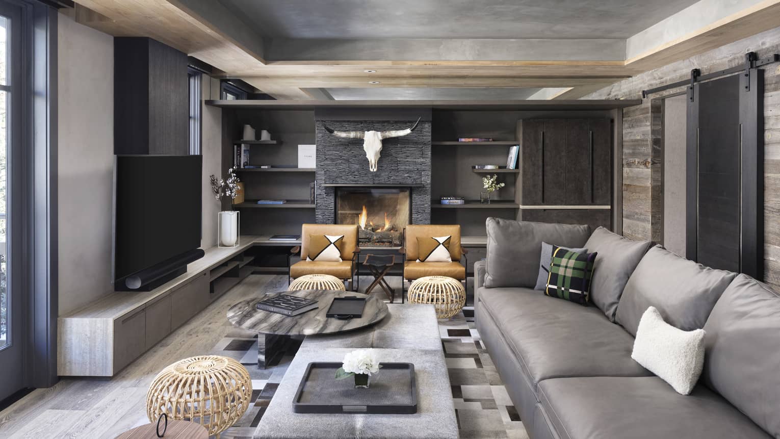 Contemporary living room with grey sofa, built-in wall shelves, cow skull above fireplace