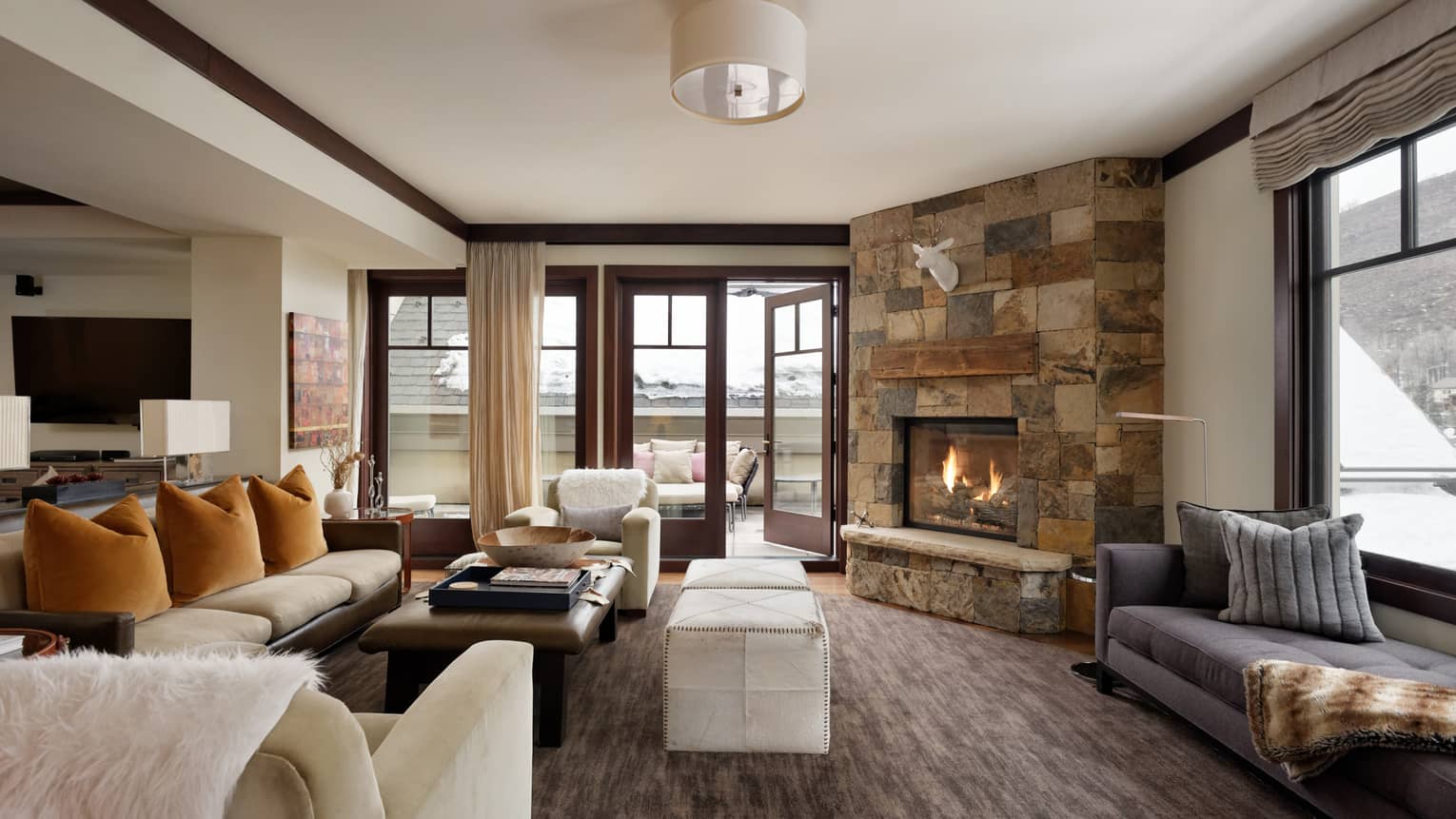 Mountain chic living room with stone fireplace and walk-out terrace