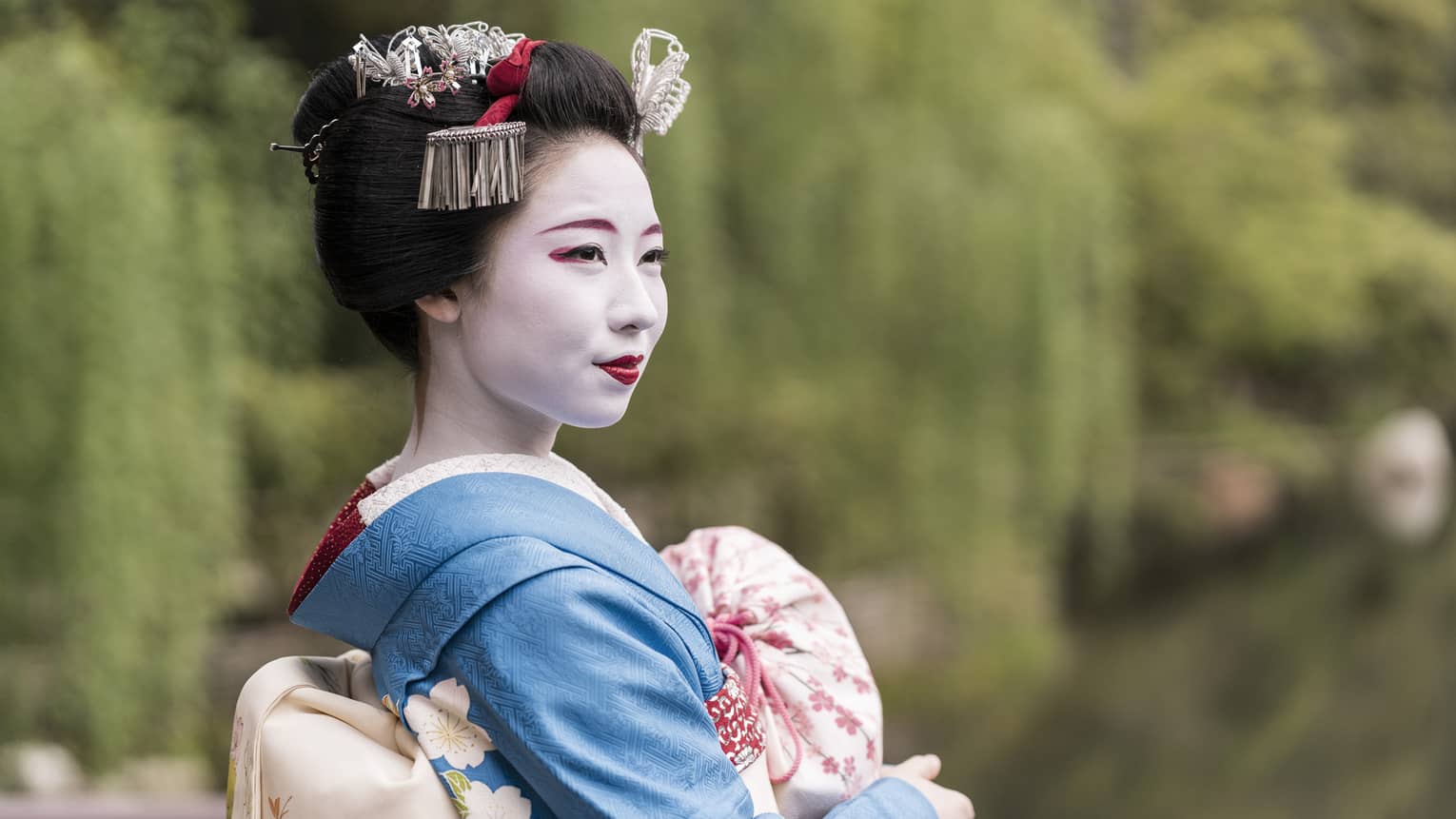 Close-up of a maiko wearing traditional makeup and a blue kimono with hair ornaments