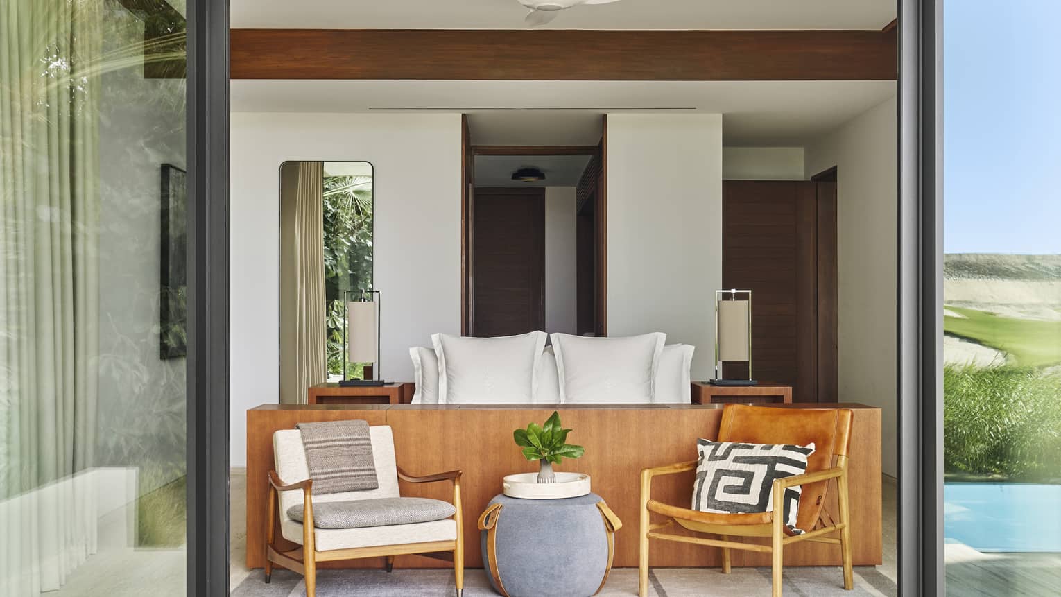 Luxury Five-Bedroom Oasis Villa Bedroom with white bed and seating vignette at foot as seen from terrace