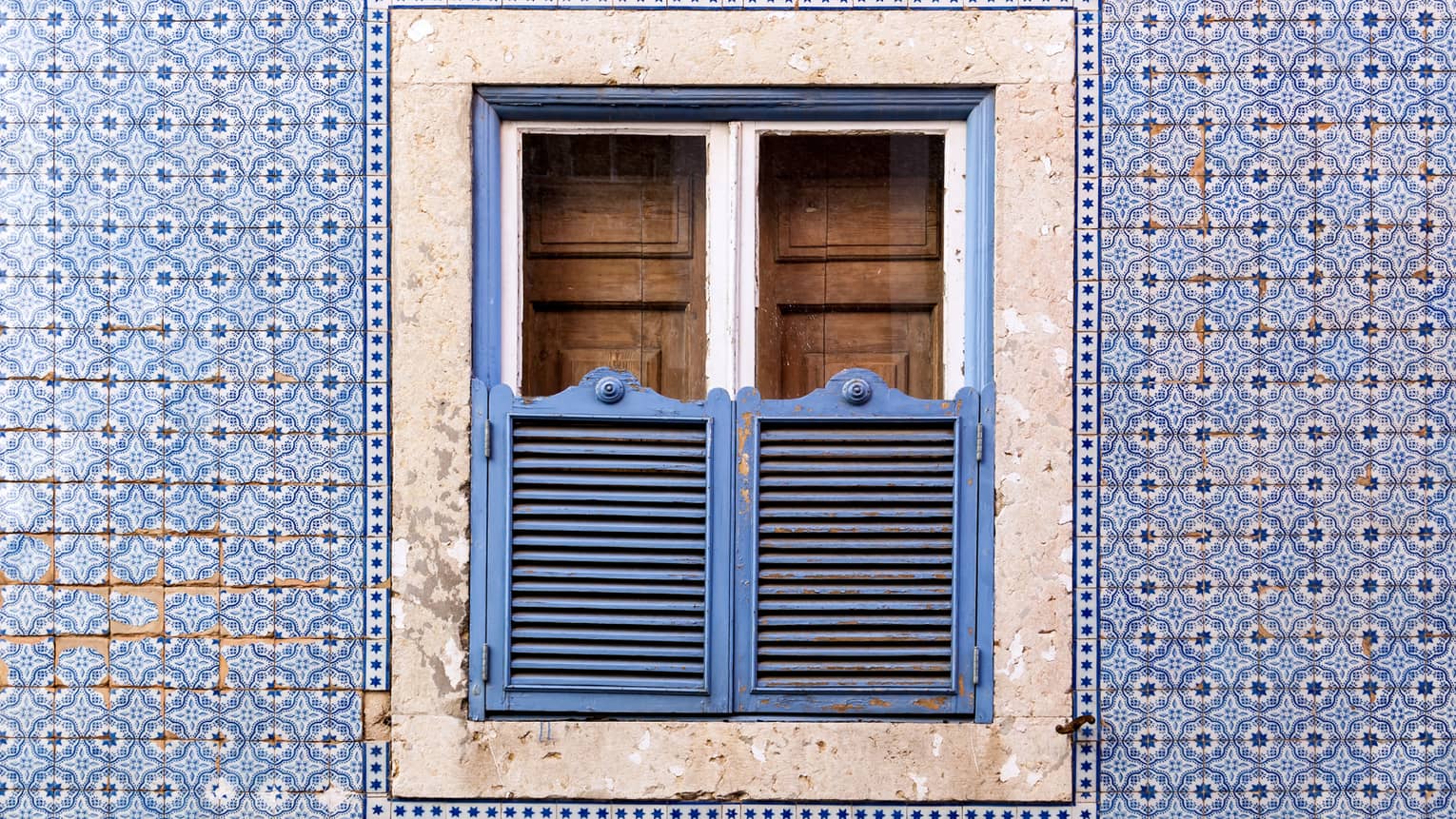 A blue wall and window covered in blue and brown doors.