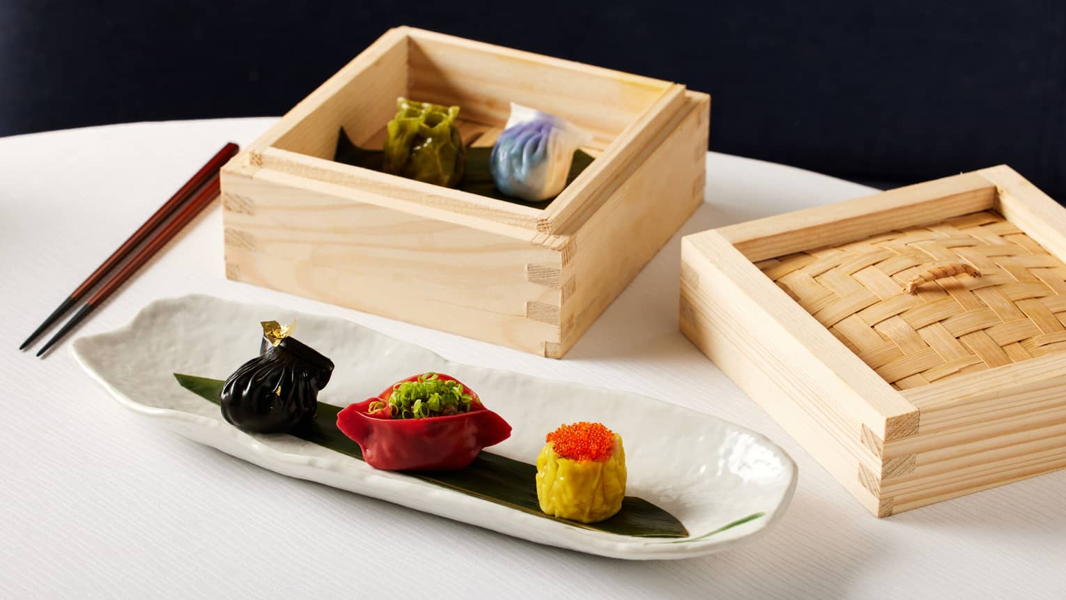 Mixed dim sum selection presented in a square bamboo box and thin white dish