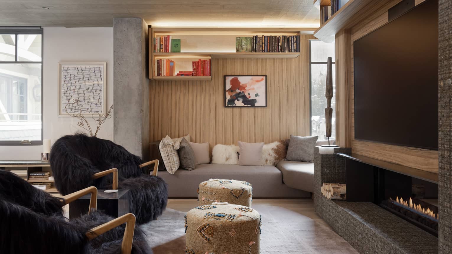 Stylish living room with two arm chairs and stools facing large TV