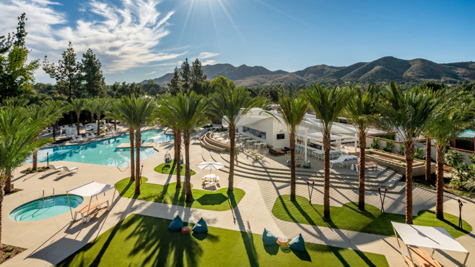 Aerial view of the pool with sunlight and palm trees.