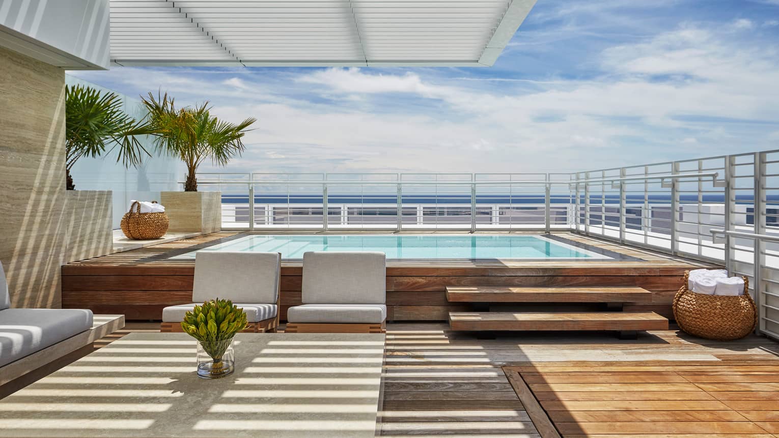 Luxury oceanfront penthouse terrace with a private pool, modern seating area, wooden deck and views of the ocean under a clear blue sky