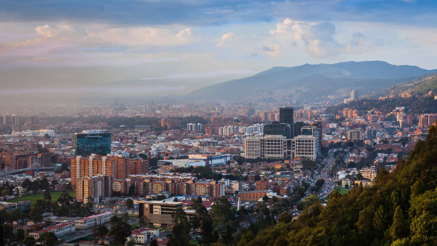 Aerial view of Bogota city, buildings and houses below misty mountains