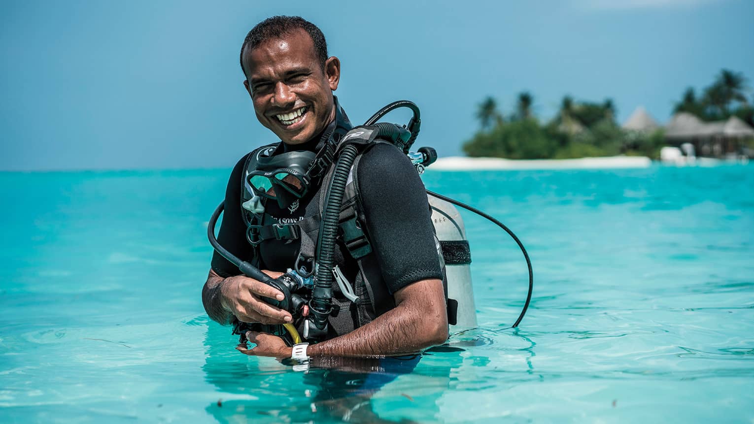 Smiling Dive Manager Ibrahim Nazeer with scuba gear in the crystal clear waters of the lagoon