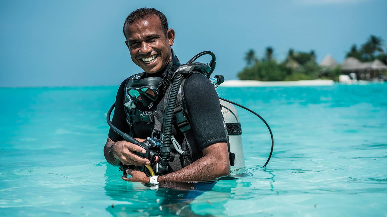 Smiling Dive Manager Ibrahim Nazeer with scuba gear in the crystal clear waters of the lagoon