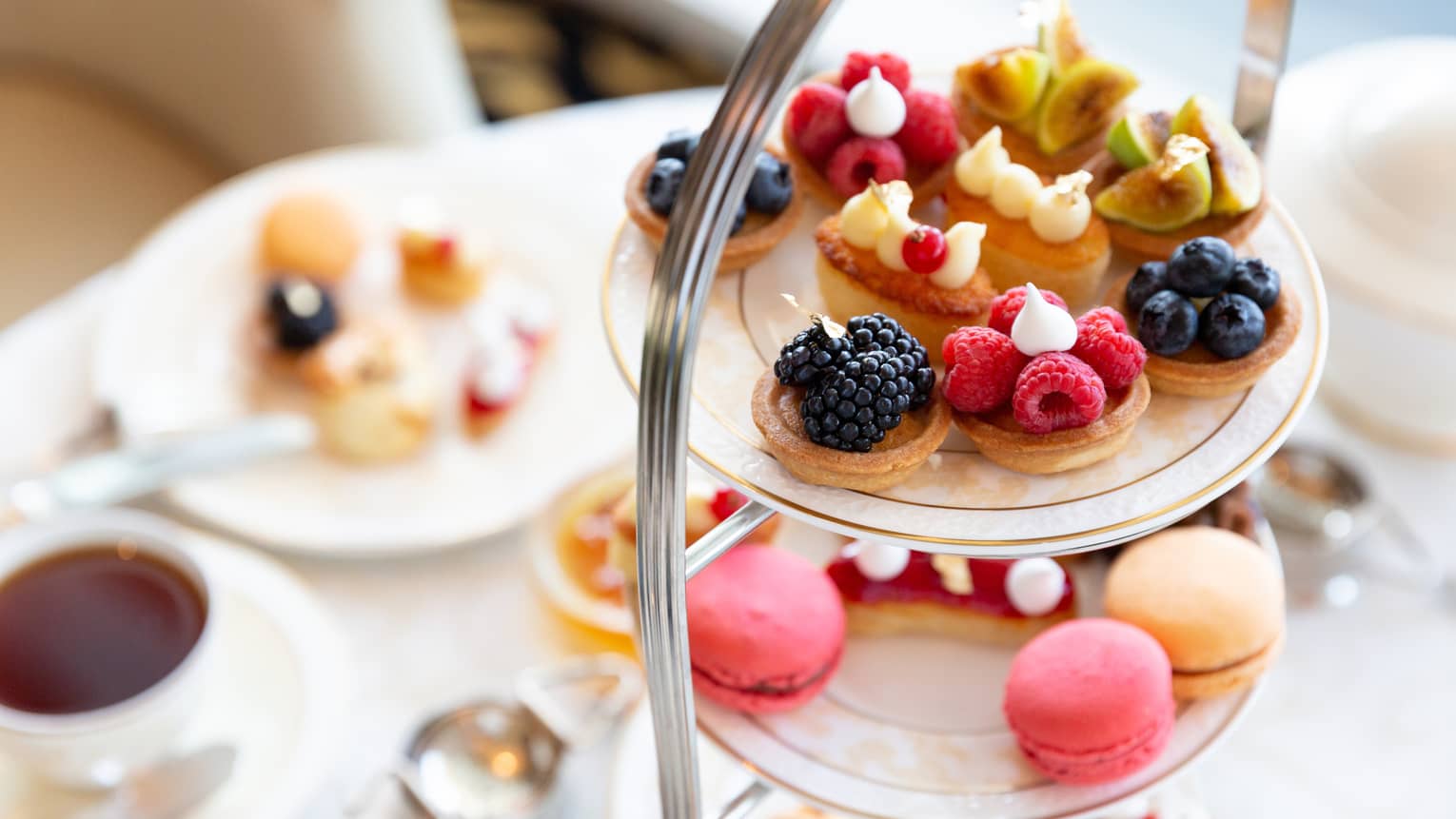 Display of small desserts with fruit toppings and tea.