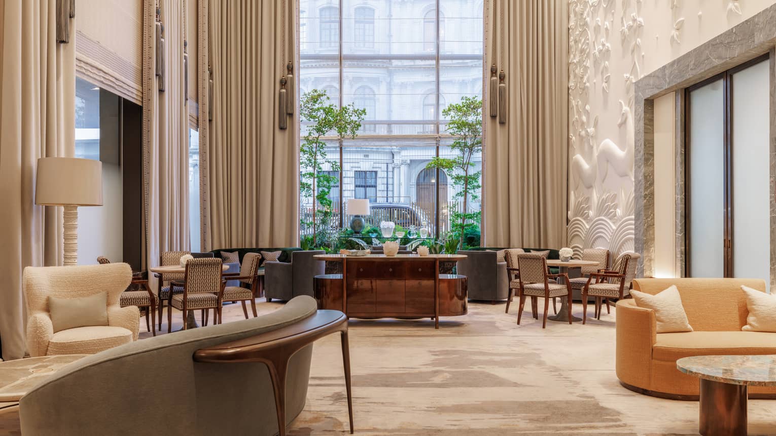 A bright, airy and spacious indoor lounge space with neutral-toned decor, comfortable seating, tables, and large windows