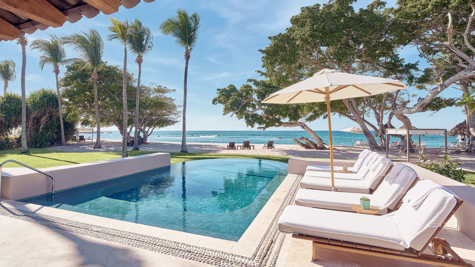 Arena Beach House Puerto Vallarta, Mexcio. Private pool with row of lounge chairs, umbrella, palm trees, ocean view