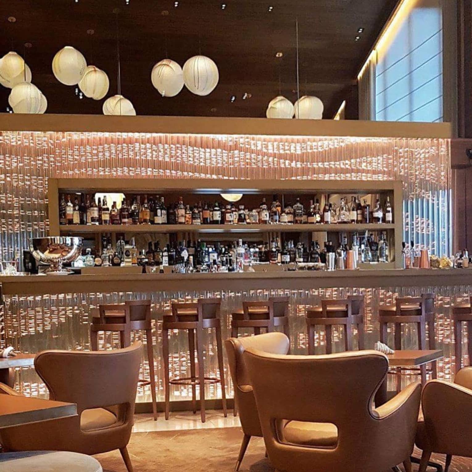 Stools at glass bar, mid-century style lounge chairs