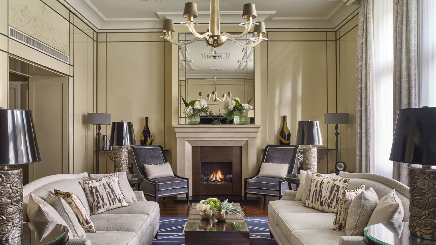 Elegant living room with two sofas, a fireplace and armchairs around a central coffee table