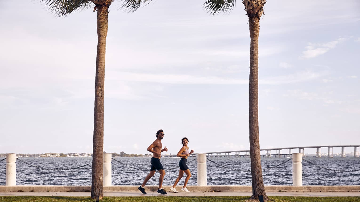 Man and woman running on sidewalk next to water