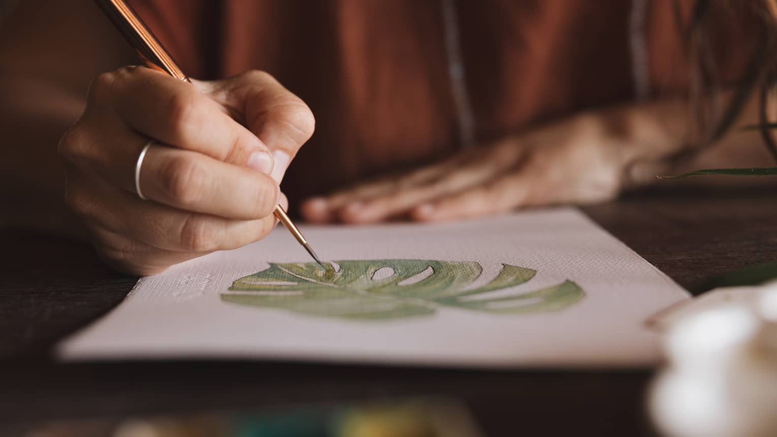 Close-up shot of someone drawing a tropical leaf on thick paper