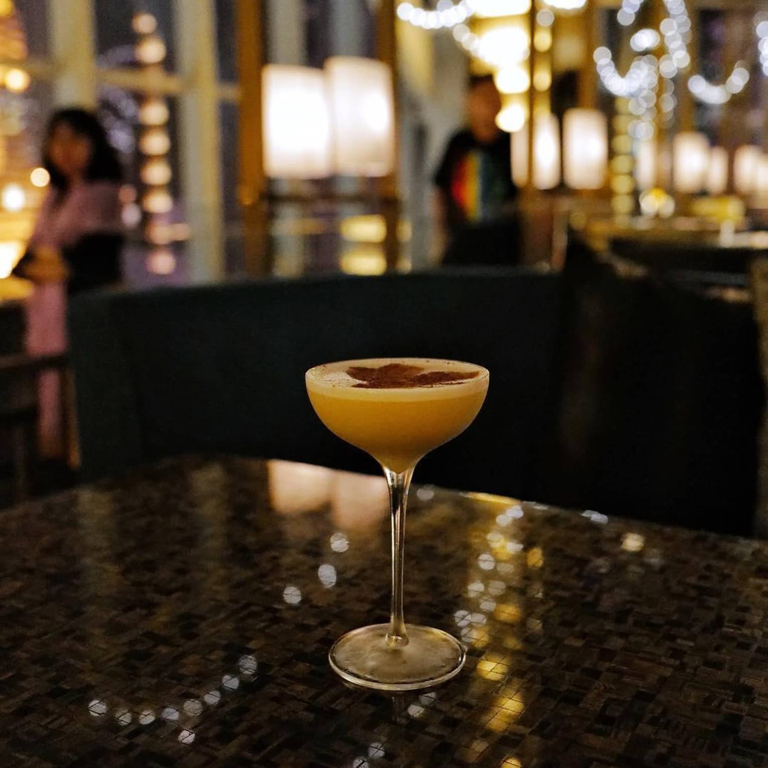 A cocktail sits on a table in a dimly lit bar