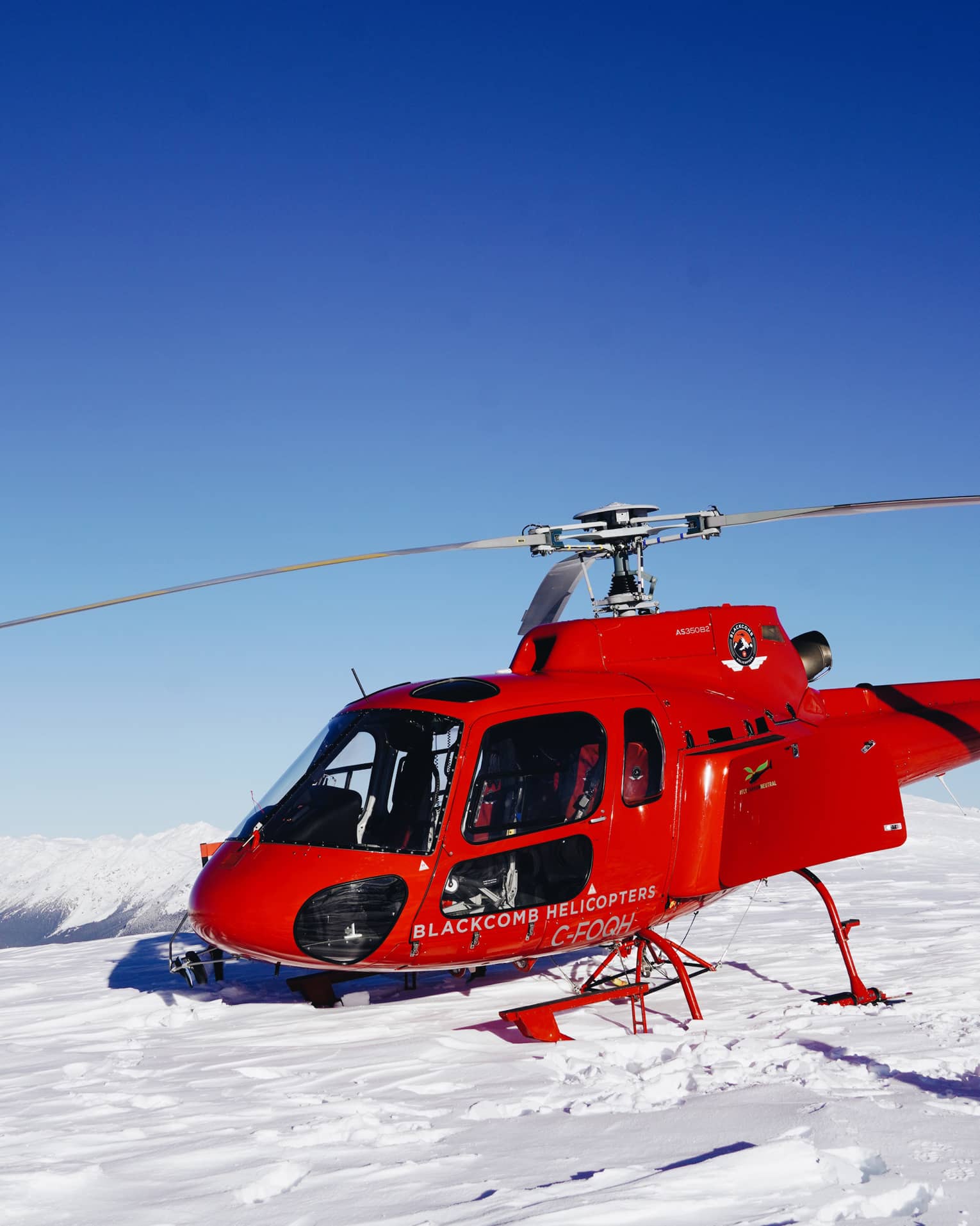 Red helicopter landing on white snow