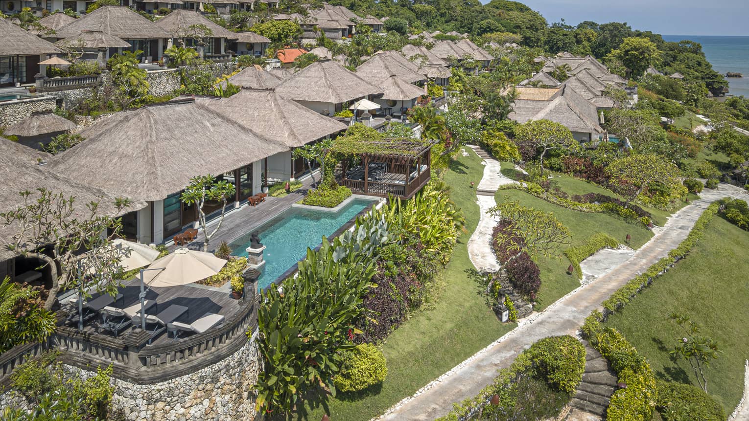 Aerial view of Royal Villa with pool, rolling green hills, ocean views