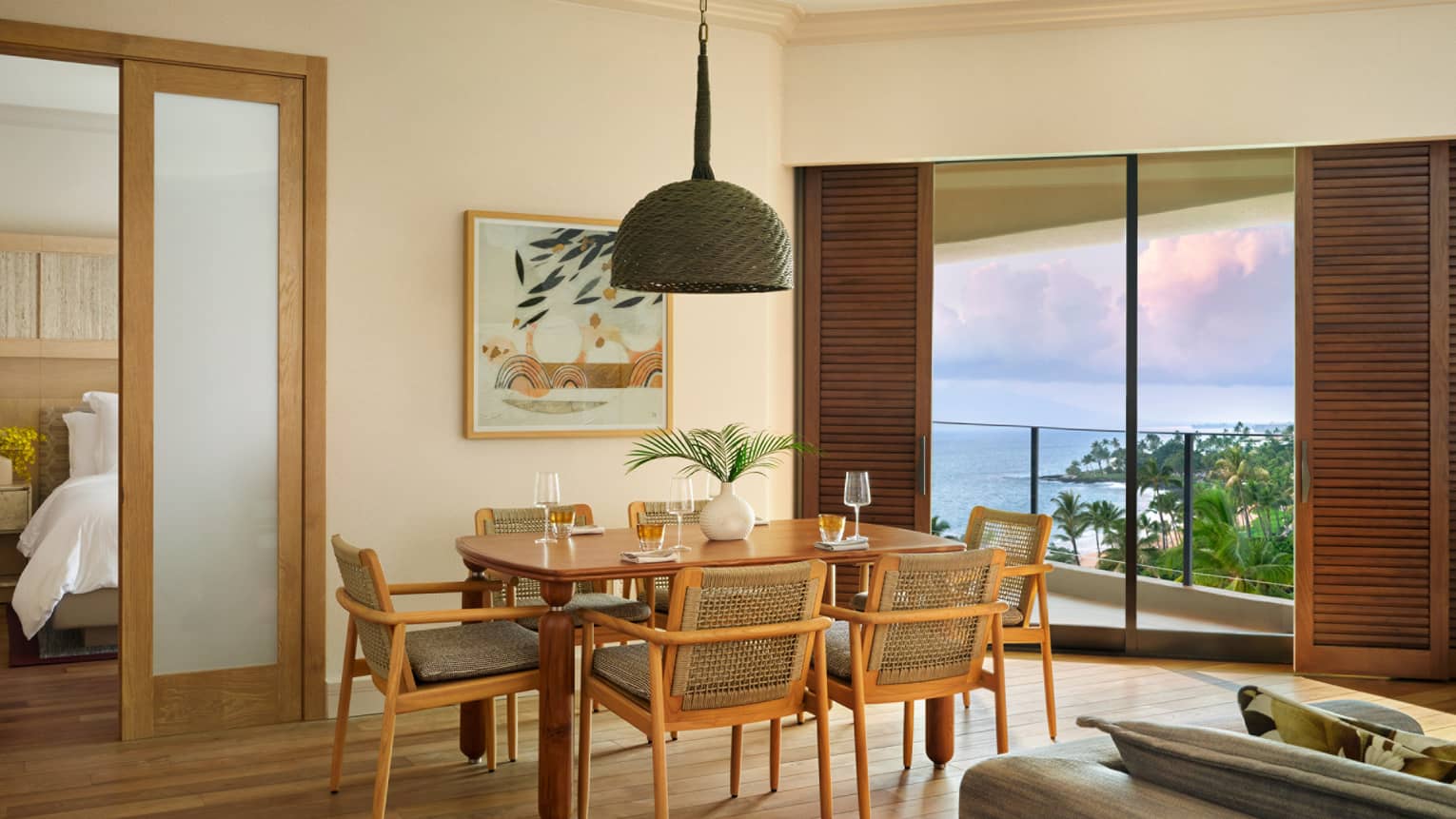Dining room in an ocean-view resort room, featuring table set for six, and an entryway into a bedroom
