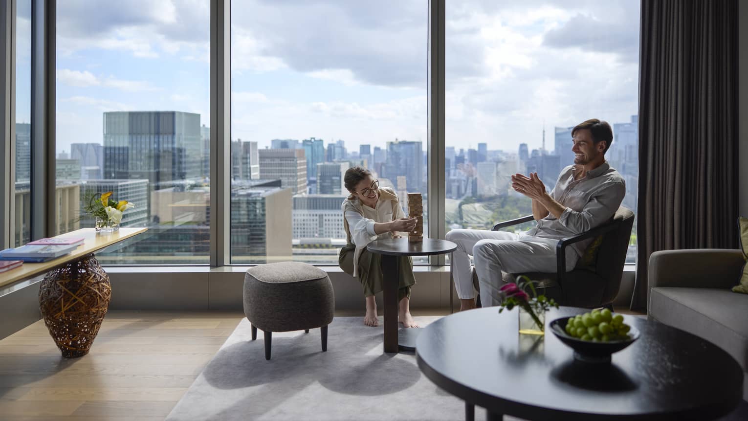 Couple enjoying a relaxing moment in a luxury suite at Four Seasons Hotel Tokyo at Otemachi with city views.