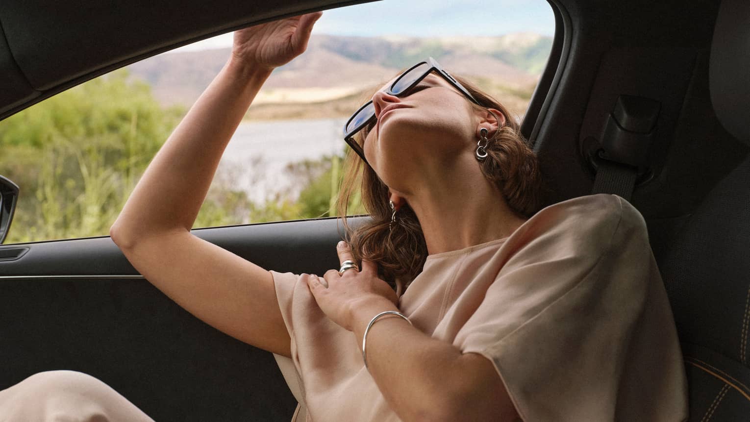 Person wearing sunglasses and looking out of a car window.