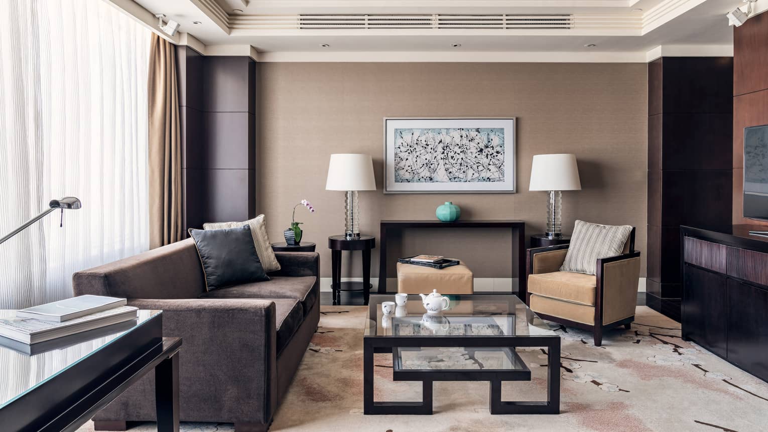 Brown coach, tan accent chair, glass nesting coffee table, brown and tan decor, floor-to-ceiling windows