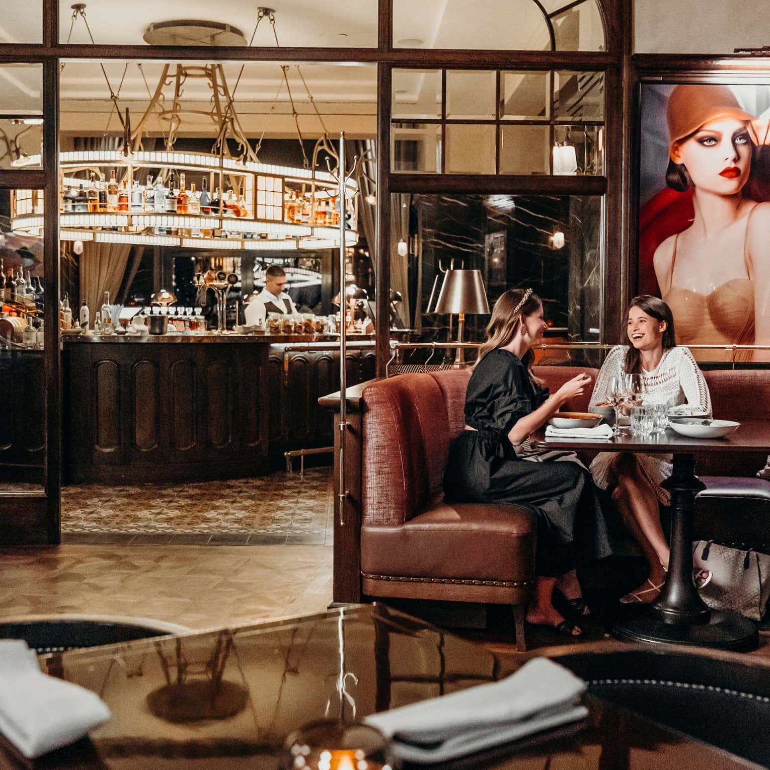 Two women sit on leather booth in restaurant