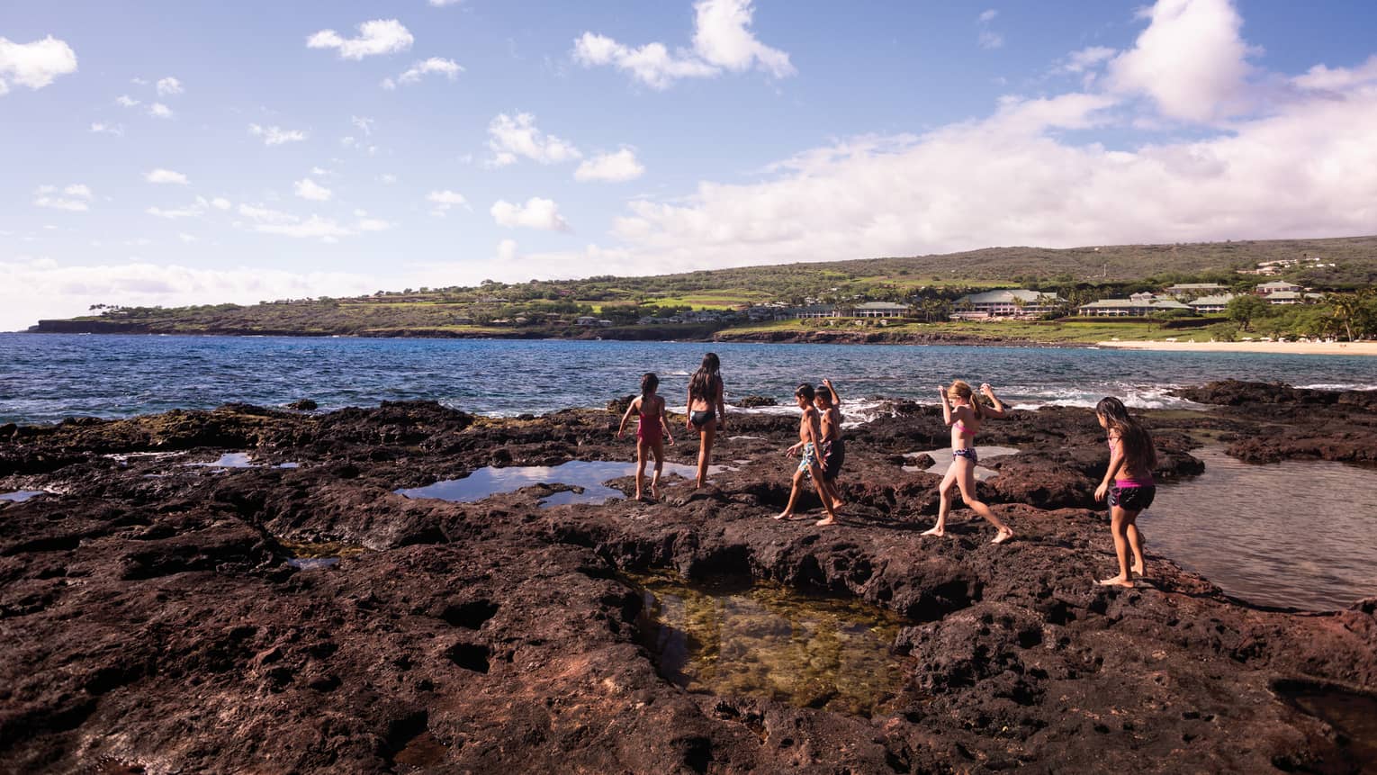 Kids walk on lava-rock beach in Lanai, Hawaii